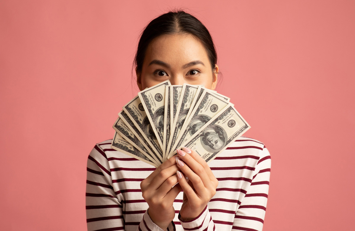 Young girl holding up cash in front of her face